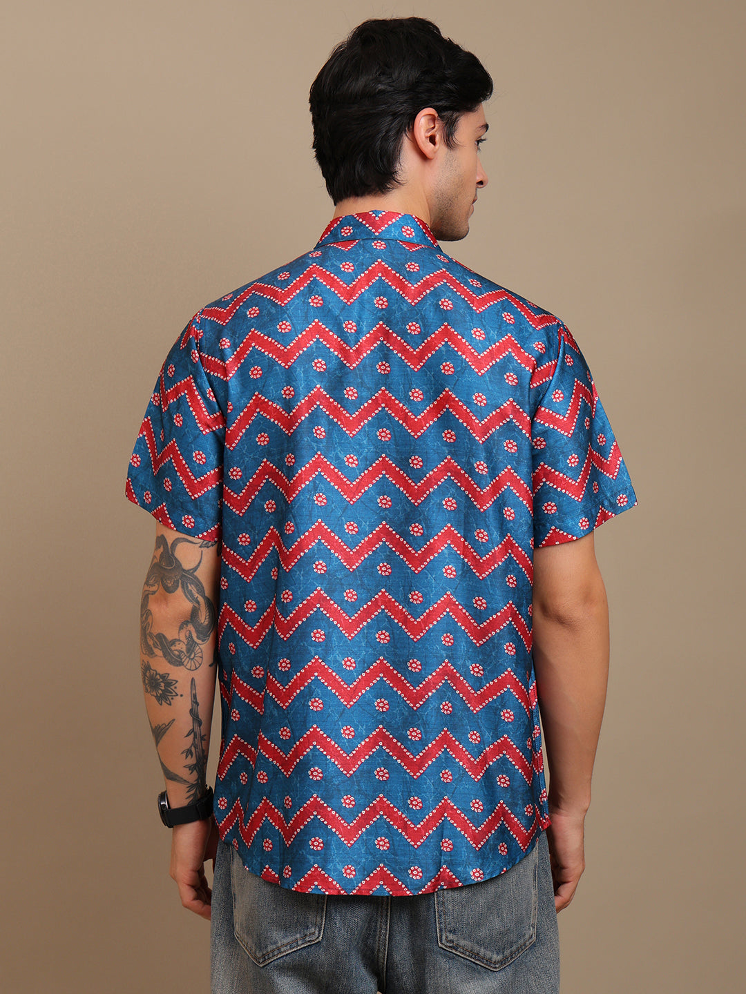 Man wearing a blue and red patterned shirt against a brown background