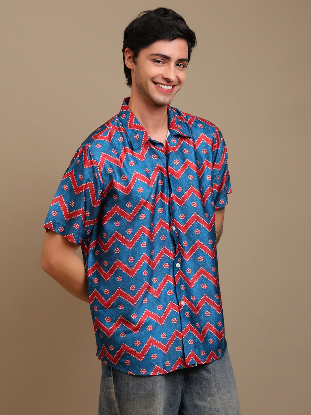 Man wearing a blue and red patterned shirt against a brown background
