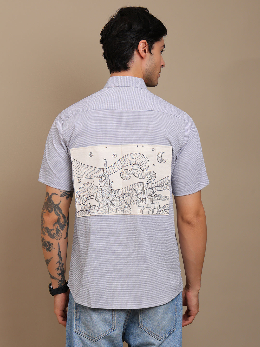 Man wearing a Grey shirt with a unique design on the back against a beige background