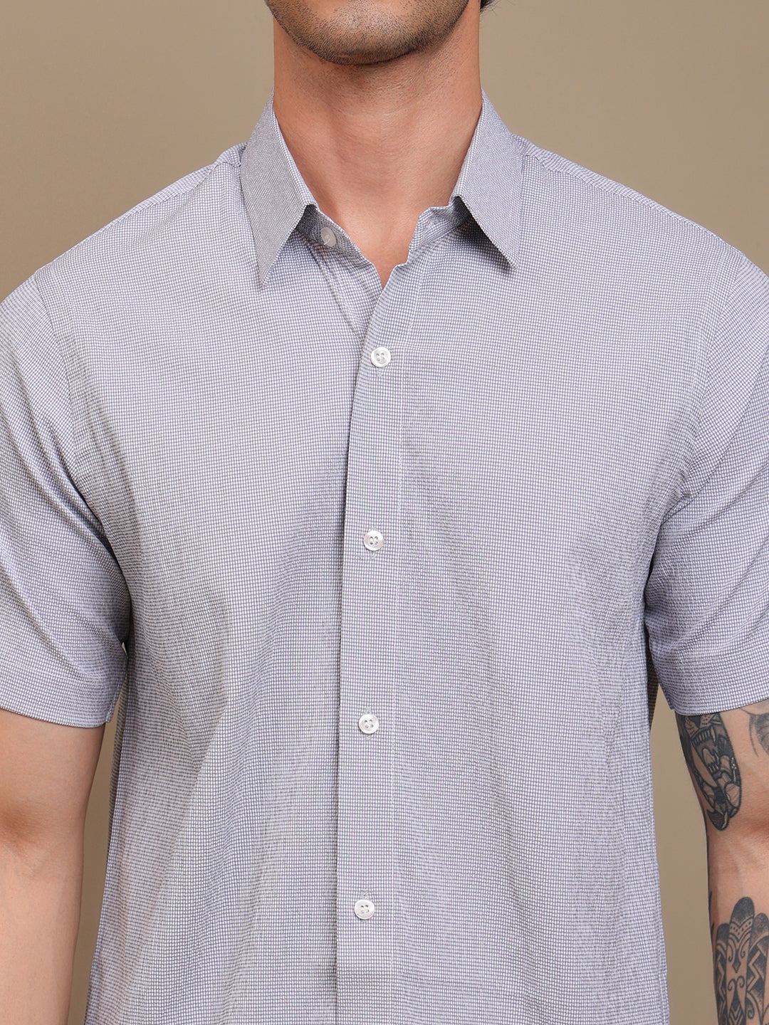 Man wearing a gray short-sleeve shirt against a beige background