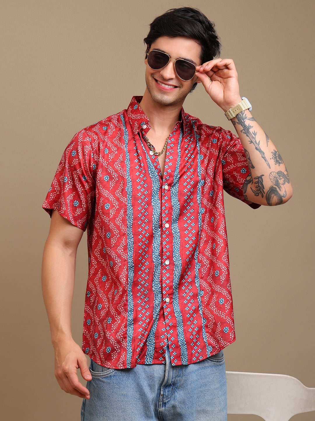 Man wearing a red patterned shirt and sunglasses against a beige background