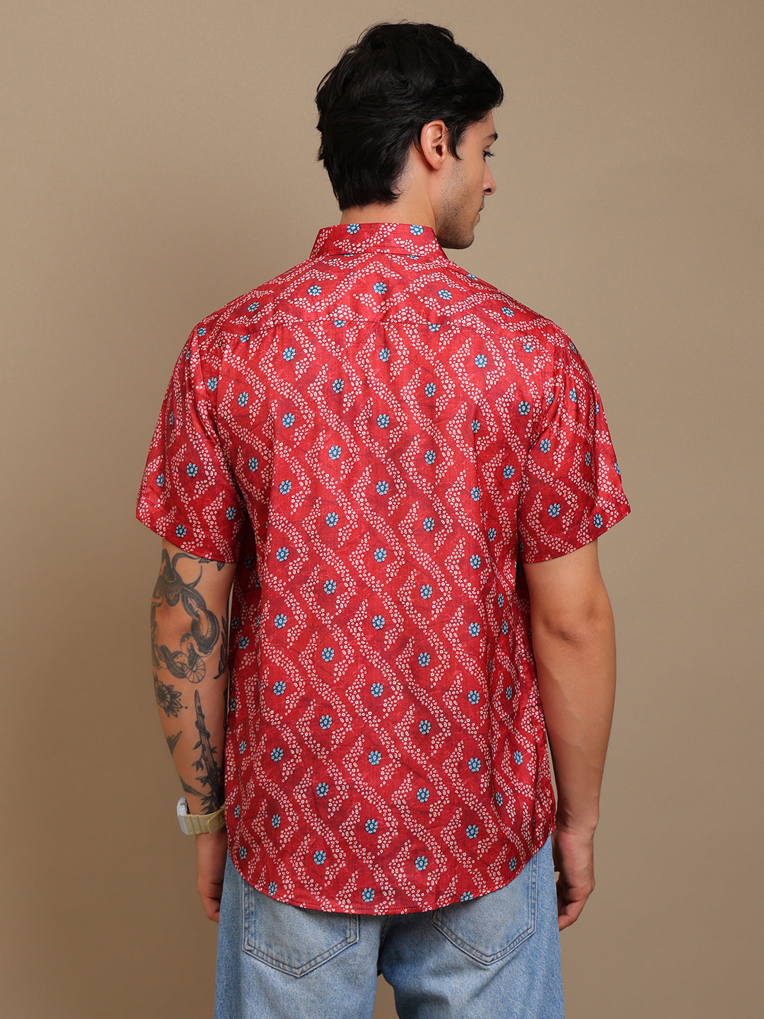 Person wearing a red patterned shirt against a beige background