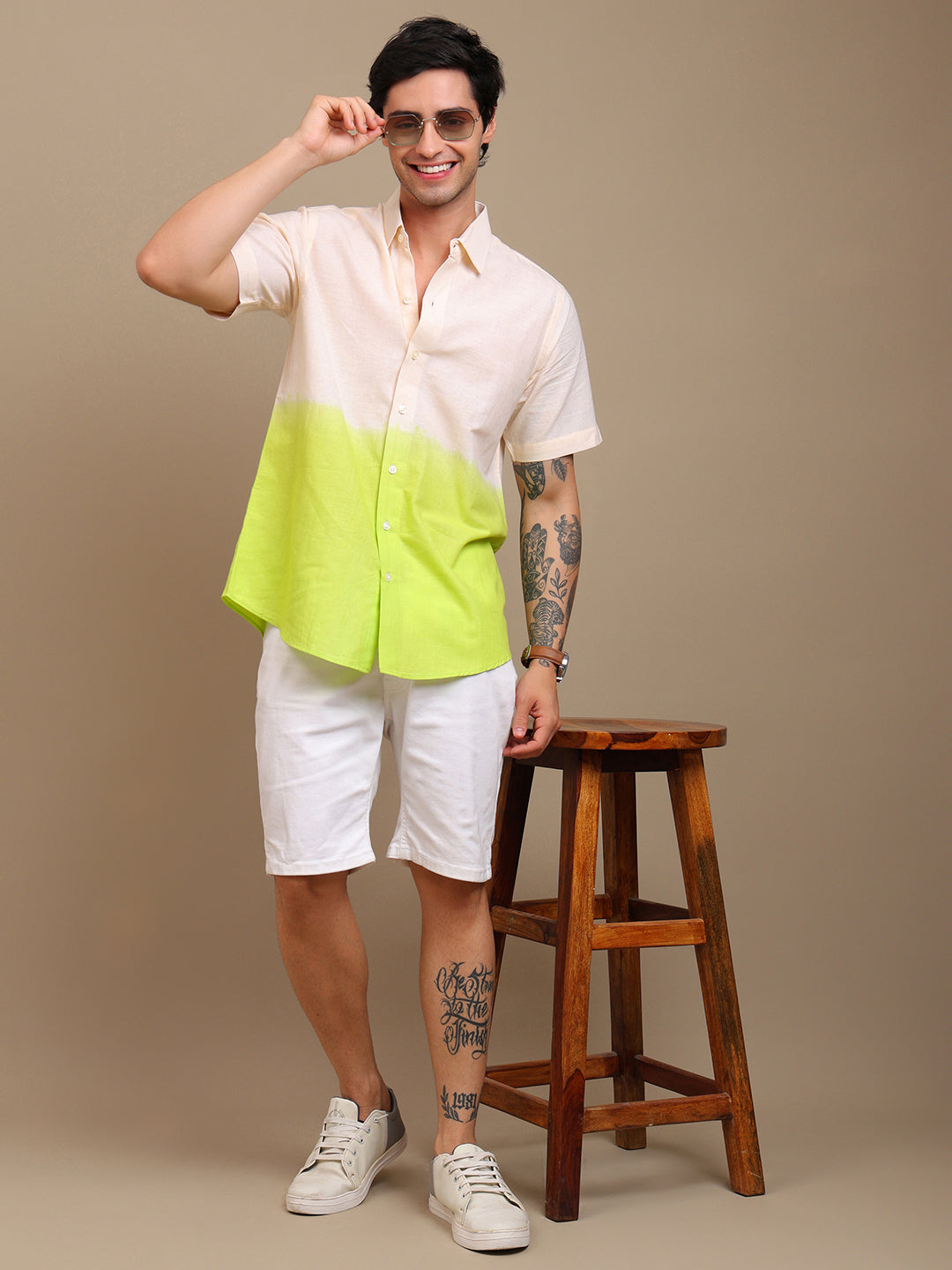 Man wearing a two-tone shirt with a wooden stool on a beige background